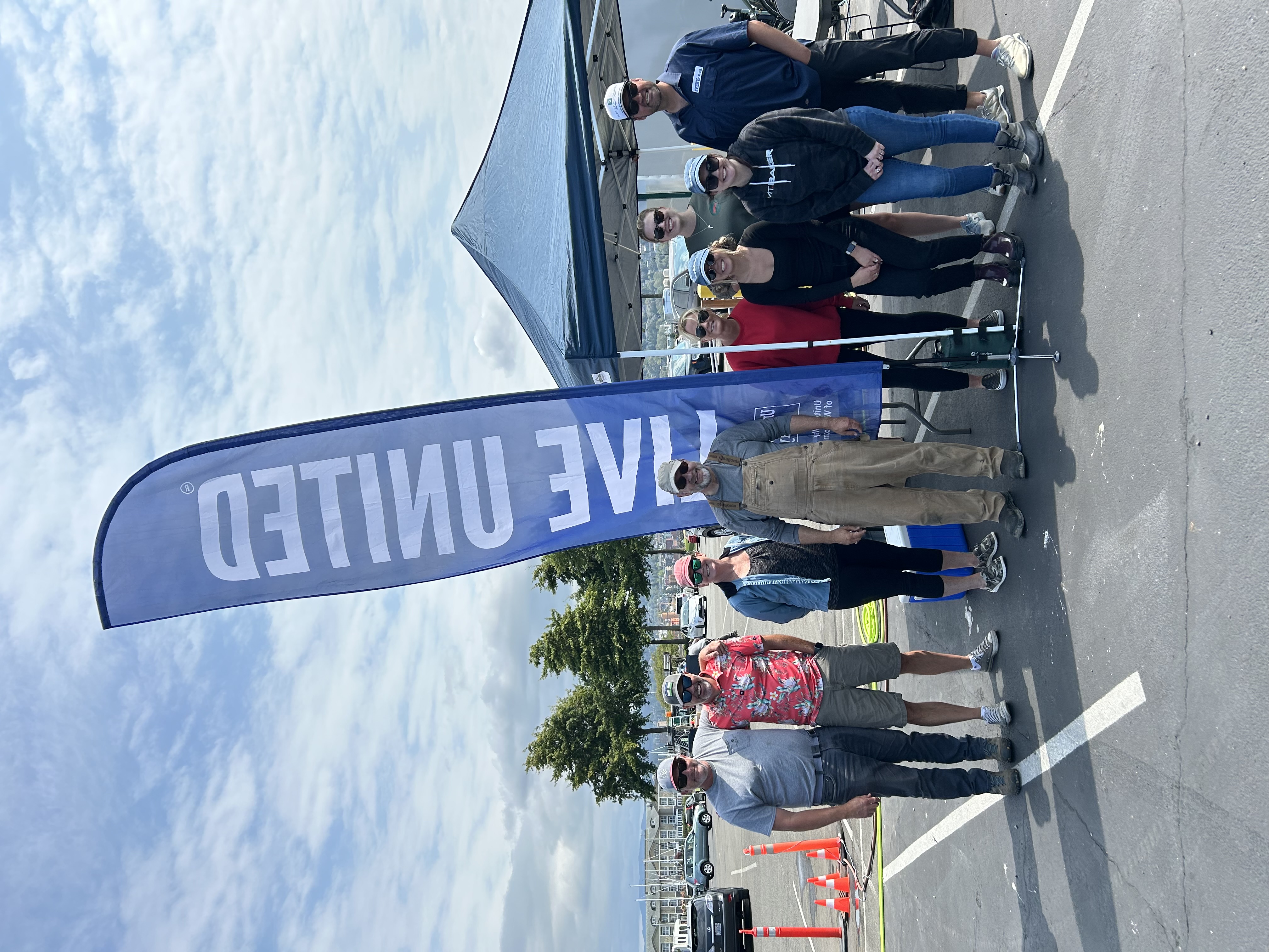 A group of Port of Bellingham employees pose for a photo around the blue "Live United" flag
